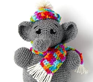 Image of a crochet elephant that is wearing a rainbow scarf and hat.